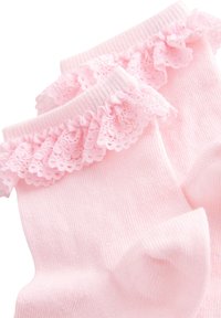 Calzini di cotone rosa con design a coste, impreziositi da un bordo in pizzo arricciato sulla parte superiore. Tessuto morbido con piccoli motivi a puntini.