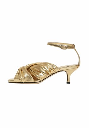 Sandale argentée à talons hauts en métal avec un design noué et plissé. Comprend une bride de cheville et un petit talon empilé. Texture lisse sur l'ensemble.