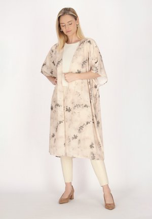 Kevyt, beige kimono harmailla kukkakuoseilla, avonainen etuosa, leveät hihat, yhdistettynä kermaisiin legginsseihin ja ruskeisiin korkokenkiin.