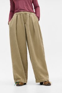 Pantaloni beige a gamba larga con vita elastica, caratterizzati da una texture a coste verticali, tasche laterali e una vestibilità ampia per il massimo comfort.