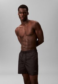 Zwarte zwembroek met een elastische tailleband en trekkoord. Gemaakt van lichtgewicht materiaal. Logo weergegeven op het linkerpootje.