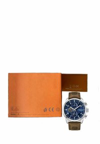 Timberland rokas pulkstenis ar zilu ciparnīcu, sudraba detaļām, brūnu ādas siksniņu, hronogrāfa funkciju un datuma rādījumu. Ietver oranžu kastīti.