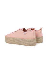 Baskets en toile roses avec une épaisse semelle en jute tressé, des œillets métalliques pour les lacets, et une petite étiquette logo à l'arrière.