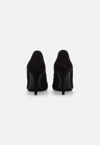 Čierne semišové lodičky na vysokom opätku s špicatou špičkou a štíhlym stiletto opätkom, s hladkou textúrou a minimalistickým dizajnom.