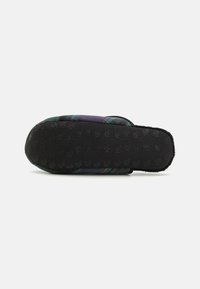 Multicolored plaid slide sandal with a black textured sole. Features a soft upper and a curved, comfy shape for ease of wear.