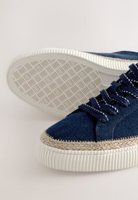 Blå denim sneakers med hvide gummisåler. Indeholder flettet jute trim, runde snørebånd og et tekstureret sålmønster.