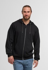 Zwarte ritssluiting hoodie gemaakt van zacht materiaal met een trekkoordcapuchon, vo pockets aan de voorkant en geribbelde manchetten. Bevat een subtiele logo op de zoom.