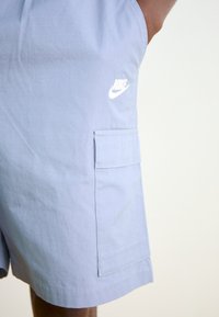 Ljusblå shorts i mjukt tyg med rutmönster. Har en sidficka och en vit Nike-logotyp på framsidan.