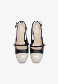 Tacchi slingback neri in pelle con finitura opaca, caratterizzati da una punta in vernice beige e da un cinturino sottile alla caviglia con fibbia dorata.