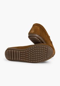 Braune Wildleder-Slipper mit abgerundeter Zehenpartie, flacher Gummisohle mit strukturiertem Grip und minimalistischer Gestaltung ohne zusätzliche Akzente.