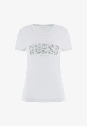 Witte t-shirt met korte mouwen van katoen, met een "GUESS" logo in edelstenen en "EST. 1981" eronder, een gladde textuur en een getailleerd ontwerp.