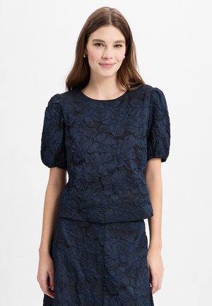 Marineblaues, floral besticktes Oberteil mit kurzen Puffärmeln, das einen runden Halsauschnitt und durchgehend strukturierten Stoff aufweist.