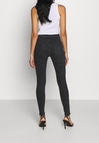 Höga svarta skinny jeans, stretchdenim, med två bakfickor och dragkedjestängning. Matchat med svarta remsandaler med hög klack.