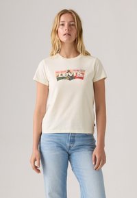 T-shirt en coton crème avec des manches courtes et un col rond. Présente un graphique du logo Levi's multicolore à l'avant.