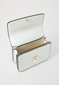 Borsa a tracolla bianca in pelle con bordo nero, forma rettangolare, chiusura in metallo dorato e interno beige. Presenta scomparti per l'organizzazione.