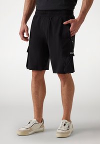 Schwarze Sportshorts mit elastischem Bund, Seitentaschen und einer Cargotasche mit Logodetail. Hergestellt aus leichtem, atmungsaktivem Material.