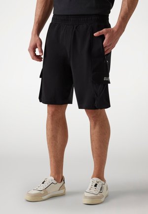 Pantaloni sportivi neri con elastico in vita, tasche laterali e tasca cargo con dettaglio del logo. Realizzati in tessuto leggero e traspirante.
