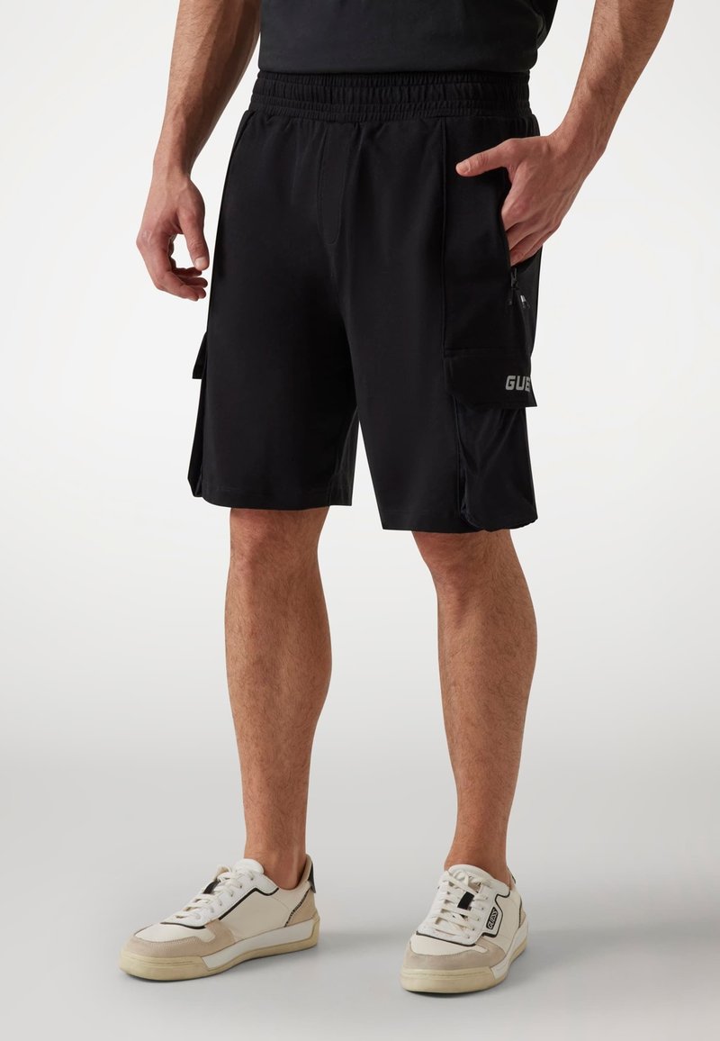Schwarze Sportshorts mit elastischem Bund, Seitentaschen und einer Cargotasche mit Logodetail. Hergestellt aus leichtem, atmungsaktivem Material.