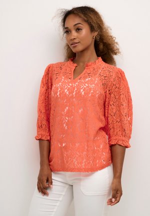 Blusa de encaje en un vibrante color naranja, con escote en V, mangas abullonadas de 3/4 de longitud y un escote con volante. Patrón floral texturizado en toda la prenda.