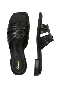 Svarta lädersandaler med fyrkantig tå, med flätade remmar och en låg klack. Innersulan har "Clarks"-logotyp.