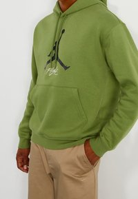 Felpa verde realizzata in tessuto morbido, con logo Jordan nero e testo "Flight". Include una tasca frontale e un design a vestibilità comoda.