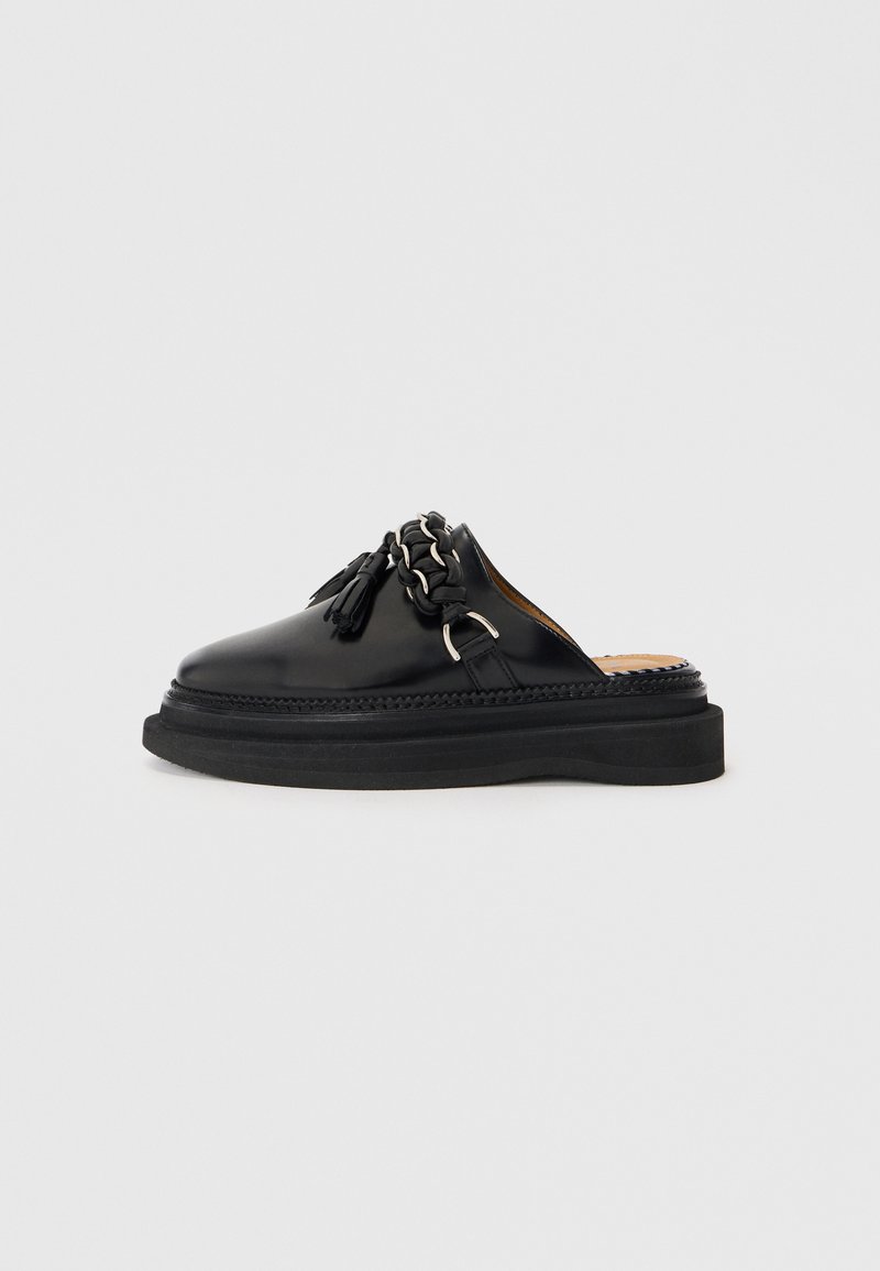 Čierne kožené slip-on topánky s strapcami a retiazkovým detailom, s hrubou čiernou podrážkou a pleteným okrajom. Hladký povrch.