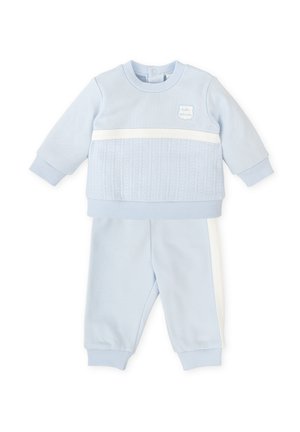 Conjunto de sudadera y pantalones en azul claro. La sudadera cuenta con un panel texturizado y una franja blanca; los pantalones tienen puños elásticos y franjas laterales.