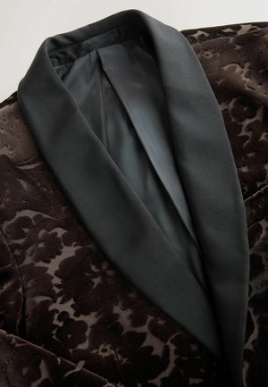 Tmavě hnědý sametový blazer s květinovým vzorem, s hladkým černým saténovým límcem a vnitřním podšíváním, zvýrazňující bohatou texturu a detail.