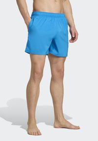 Blaue Badehosen mit elastischem Bund, zwei seitlichen Taschen, einer glatten Textur und einem Design in Mittellänge bis zum Oberschenkel. Keine sichtbaren Muster oder Akzente.