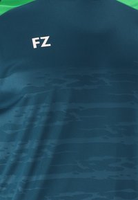 T-shirt med kort ärm i mörkgrön och marinblå med subtilt strukturerat mönster. Har vit "FZ"-logotyp på framsidan. Slätt, lätt material.