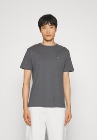 Grijze crewneck t-shirt van een lichte stof met korte mouwen, voorzien van een klein logo op de borst en een comfortabele pasvorm.