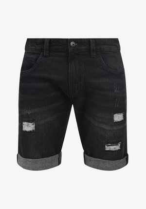 Mustad teksapüksid kulunud disainiga. Omavad rullitud servasid, nähtavat õmblust ja mitmeid plaastrite, mis paljastavad allolevat kangast.