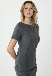 Graues, kurzärmliges Oberteil aus strukturiertem Stoff mit körperbetontem Schnitt, seitlichen Nähten und rundem Halsausschnitt.