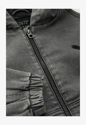 Grå zip hoodie med mjuk textur, med en svart dragkedja och ribbade ärmar. Inkluderar en logotyp på bröstet och en huva.