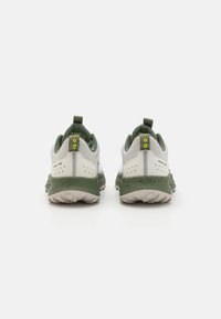 Scarpe sportive verde e bianche con tomaia testurizzata e traspirante, tallone rinforzato e suola in gomma. Presentano linguette di aiuto e audaci accenti gialli.