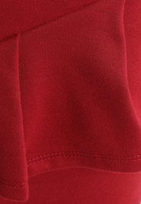 Tela elástica roja con una textura suave y un ligero brillo, con un diseño arrugado y un dobladillo bien terminado.