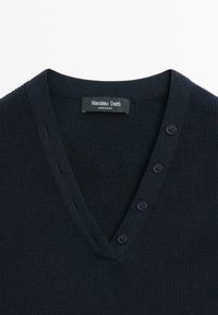Donkerblauwe trui met een V-hals, geribbelde textuur en vier knoopdetails aan de linkerkant. Etiket zegt "Massimo Dutti."