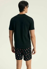 Czarna bawełniana koszulka z krótkim rękawem, zestawiona z czarnymi szortami w różowo-białym wzorze serc.