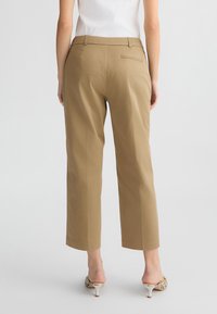 Pantaloni cropped color sabbia con una texture liscia, dotati di una tasca posteriore, vestibilità sartoriale e design a gamba dritta.