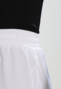 Black top paired with a white, elastic waistband skirt. The skirt has a gathered texture and a smooth fabric finish.