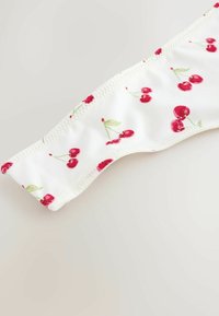 White fabric with a glossy finish, featuring a cherry pattern in red and green. Smooth texture, with flat seams along the edges.