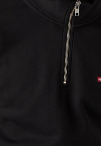 Felpa nera con mezza zip argentata e un piccolo logo rosso e bianco di Levi's sul petto.