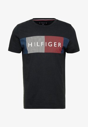 Schwarzes T-Shirt mit kurzen Ärmeln und einem horizontalen Streifenpanel in Rot, Weiß und Blau. Mit dem Wort "HILFIGER" in weißen Buchstaben versehen. Aus weichem Baumwollstoff.