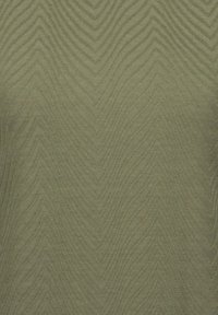 Tessuto verde testurizzato con un motivo a zigzag, con tonalità alternate che creano profondità. Morbida texture intrecciata con una leggera lucentezza.