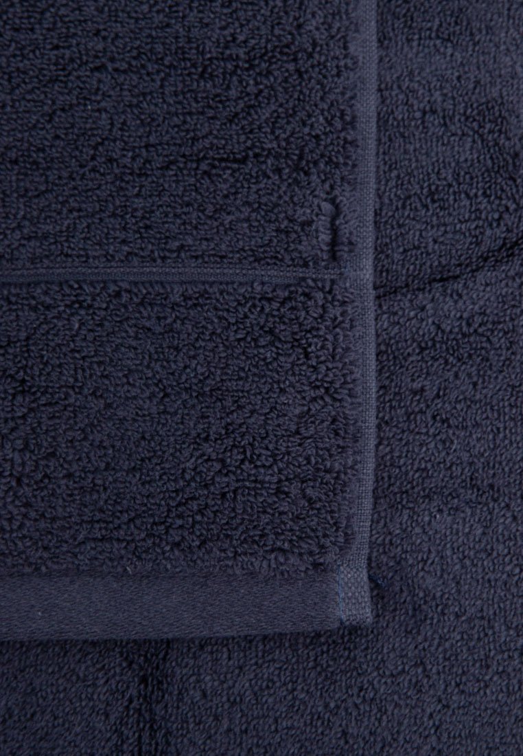 Marineblaue Handtuch aus flauschigem Frottee, mit weicher Textur, glattem, beschnittenem Rand und feinen Nähdetails.