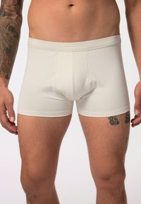 Boxers en coton blanc avec une ceinture douce, un design ajusté, des coutures flatlock et une texture lisse. Pas de motifs ni de graphiques visibles.