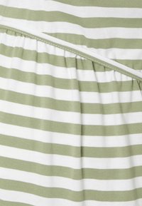 Tecido riscado em verde claro e branco, apresentando uma textura franzida e um detalhe de costura em contraste ao longo da costura.