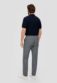 Polo azul marino con una textura sutil, combinado con pantalones de cuadros gris claro. Zapatillas blancas completan el conjunto.