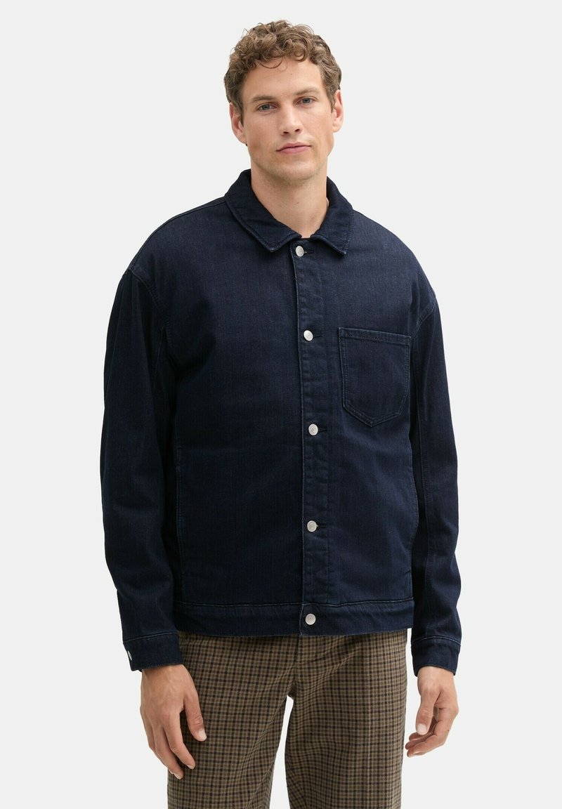 Dunkel marineblaue Jeansjacke mit Kragen, Knopfleiste vorne und aufgesetzter Tasche. Mit langen Ärmeln und entspanntem Schnitt.