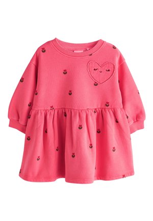 Różowa sukienka dla małego dziecka z długimi rękawami, marszczoną spódnicą, drobnymi ciemnymi kwiatowymi wzorami oraz naszywką w kształcie serca z uśmiechniętą twarzą na piersi.